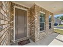 Front entry with brick facade and a brown door at 615 Grassmeade Ln, Woodstock, GA 30188