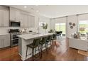 Modern kitchen with stainless steel appliances, island seating, and hardwood floors open to the living room at 6900 Winchester Pl, Fairburn, GA 30213
