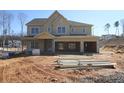 New construction home with yellow siding, a two-car garage, and an inviting front porch at 444 Lower Shoreline Sw Ct, Marietta, GA 30064