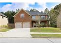 Charming two-story home features a brick facade, two-car garage, and a well-manicured lawn at 7940 White Oak Loop, Lithonia, GA 30038