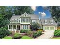 Two-story house with brick and green siding, a large front porch, and a two-car garage at 192 Chicopee Ne Dr, Marietta, GA 30060