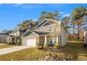 Two-story house with stone and gray siding, two-car garage, and a landscaped yard at 7787 Richmond Trl, Fairburn, GA 30213