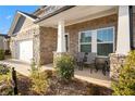 Stone front porch with gray chairs and lush landscaping at 7787 Richmond Trl, Fairburn, GA 30213