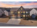 Elegant two-story home featuring a brick facade, a three-car garage, and a professionally landscaped front yard at dusk at 5915 Partners Pass, Cumming, GA 30028