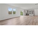 Open-concept living space with hardwood flooring, large windows, and a modern kitchen in the background at 3340 Redwood Ct, Covington, GA 30016