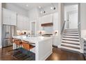 Well-lit kitchen with white cabinets, stainless steel appliances, an island with seating, and staircase access at 6750 Avis Walk, Alpharetta, GA 30005