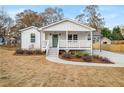 Charming white home with a covered front porch, green door and landscaped yard at 1009 Manor Se Dr, Smyrna, GA 30080