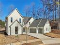 Charming two-story white home with a well-manicured lawn, gray roof and arched doorway and driveway at 120 Thome Dr, Alpharetta, GA 30022