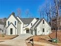 Charming two-story white home with a well-manicured lawn, gray roof and arched doorway and driveway at 120 Thome Dr, Alpharetta, GA 30022