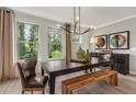 Bright dining room featuring modern chandelier, wood table with bench, and views of the landscaped outdoors at 1297 Forsyth Park Rd, Decatur, GA 30033