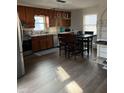 Eat-in kitchen with stainless steel appliances, wood cabinets, a tile backsplash, and modern lighting at 4876 Velva Nw Way, Lilburn, GA 30047
