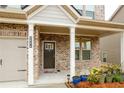 Charming front porch with brick accents, a dark-colored front door and lovely potted plants at 3004 Amabile Rd, Dacula, GA 30019