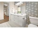 Bright bathroom with double sink vanity, framed mirror, and neutral patterned wallpaper at 234 Ashford Cir, Atlanta, GA 30338