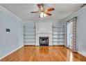 Light-filled living room features a cozy fireplace, built-in shelving, a ceiling fan and beautiful hardwood floors at 4127 Conley Pond Ct, Decatur, GA 30034