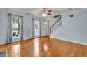 Spacious living room featuring hardwood floors, staircase, two bright windows and a ceiling fan at 4127 Conley Pond Ct, Decatur, GA 30034