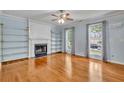 Bright living room with a fireplace, built-in shelving, ceiling fan, hardwood floors, and windows with decorative curtains at 4127 Conley Pond Ct, Decatur, GA 30034