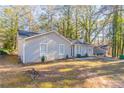 Gray sided single-story home with a spacious yard and mature trees surrounding the property at 1832 Vauxhall Dr, Lithonia, GA 30058
