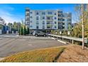 Apartment building exterior with parking, landscaping, and a clear blue sky at 6890 Peachtree Dunwoody Rd # 303, Atlanta, GA 30328