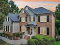 Charming two-story home featuring a brick facade, black shutters, and manicured landscaping at 3950 Stanford Dr, Cumming, GA 30041