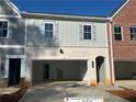 Two-story townhome featuring a brick and gray facade, with a spacious drive-in garage and an arched entryway at 405 Carrera Ln, Acworth, GA 30102