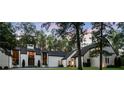 Stunning white home with expansive windows and a lush, green lawn surrounded by mature trees at 9650 Coleman Rd, Roswell, GA 30075