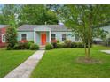 Charming one-story home with an orange front door, lush lawn, and mature landscaping at 67 Holly Nw Rd, Atlanta, GA 30314