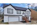 Two-story house with white and black exterior, attached garage, and a wooden staircase at 3094 Jonesboro St, Ellenwood, GA 30294