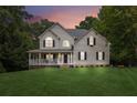 Inviting two-story home featuring a covered porch and a well-maintained lawn at dusk at 25 Grange Ct, Sharpsburg, GA 30277