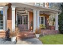 Inviting front porch with brick flooring and a yellow bench at 5507 Ashleigh Walk Nw Dr, Suwanee, GA 30024