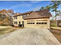 Tan two-story house, two-car garage, and mature trees at 978 Gwens Sw Trl, Lilburn, GA 30047