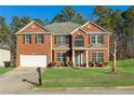 Brick two-story house with a 2 car garage and landscaped lawn at 3736 Busker Mill Ln, Ellenwood, GA 30294