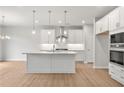 Modern kitchen with white cabinets, stainless steel appliances, a large island, and light wood floors at 344 Riverwood Pass, Dallas, GA 30157