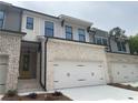 A new construction townhome features light brick, a two-car garage, black gutters, and a yellow front door at 1366 Lucan Ln # Wc225, Lawrenceville, GA 30043
