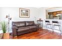 Living room with hardwood floors, brown leather sofa, and kitchen bar at 275 13Th Ne St # 1106, Atlanta, GA 30309