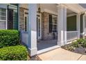 Front porch with white columns, brick flooring, and a cozy bench at 6196 Windflower Dr, Powder Springs, GA 30127