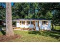 Ranch home with white brick exterior, wood accents, and a large tree in the front yard at 207 Okemah Se Trl, Marietta, GA 30060