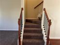 Carpeted staircase with dark wood railings, connecting floors of the home at 606 Grenier Ter, Lawrenceville, GA 30045