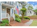 Inviting brick front porch with decorative shrubs and a wooden front door, featuring an American flag at 3616 Longfellow Trl, Marietta, GA 30062