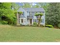 Traditional home featuring a large front yard, mature trees, and blue shutters on a sunny day at 3616 Longfellow Trl, Marietta, GA 30062
