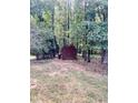 Red storage shed nestled in a wooded backyard setting at 130 Fiddle Crk, Social Circle, GA 30025