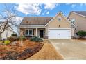 Tan house with a white garage door and landscaping at 618 Cobblestone Cir, Canton, GA 30114