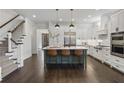Modern kitchen features stainless steel appliances, a central island with bar seating, and a staircase at 6725 Cross Gate St, Cumming, GA 30040