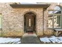Arched entryway with a wooden door, brick facade, and snow on the ground at 570 Pleasant Grove Rd, Mcdonough, GA 30252