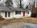 A beautifully renovated exterior features white siding, black shutters, and a striking red door for a modern, yet classic look at 240 Dogwood Dr, Canton, GA 30114
