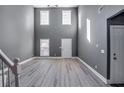 Two-story living room with gray walls, hardwood floors, and multiple windows at 6269 Colonial Vw, Fairburn, GA 30213