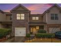 Charming townhome with brick and siding exterior, attached garage, and well-maintained landscaping at dusk at 1328 Stone Bay Sw Dr, South Fulton, GA 30331