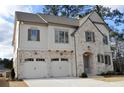 House exterior featuring brick and white accents, a three-car garage, and a charming front porch at 217 Wakehurst Way, Marietta, GA 30064