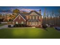 Brick two-story house with a large front yard and attached garage at dusk at 4450 Fairfax Dr, Cumming, GA 30028