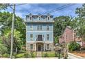 Three-story home with stone and blue siding, a fenced yard, and a beautiful front entrance at 2972 Lookout Ne Pl, Atlanta, GA 30305