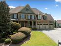 Charming two-story home featuring a large three car garage, stone accents, beautiful landscaping, and a covered front porch at 5585 Lavender Farms Rd, Powder Springs, GA 30127